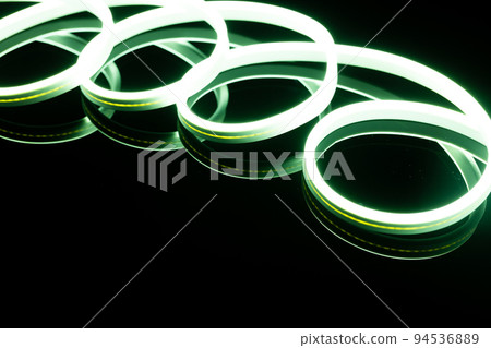 Image of vibrant spiral green neon glow sticks over black background with copy space 94536889