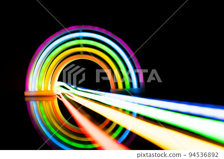 Image of vibrant neon glow sticks forming rainbow over black background with copy space 94536892