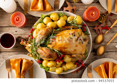 Overhead view of thanksgiving table with roast chicken, vegetables, candles and autumn decoration 94537055