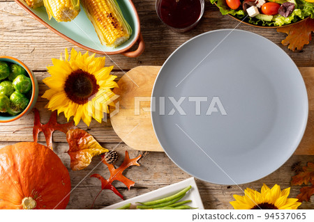 Thanksgiving table with plate, vegetables and autumn decoration with sunflowers on wood Thanksgiving table with plate, vegetables and autumn decoration with sunflowers on wood 94537065