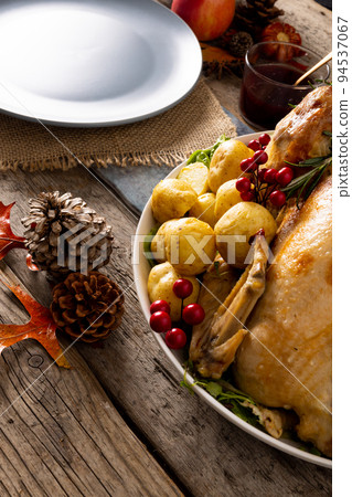 Close up of thanksgiving table with roast turkey, potatoes and autumn decoration on wood Close up of thanksgiving table with roast turkey, potatoes and autumn decoration on wood 94537067