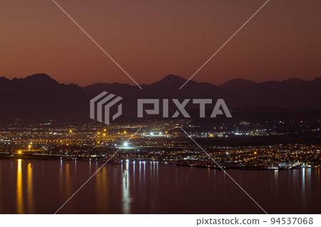 Landscape of sea, sea shore with city lights, mountains, cloudless sky at sunset and horizon Landscape of sea, sea shore with city lights, mountains, cloudless sky at sunset and horizon 94537068
