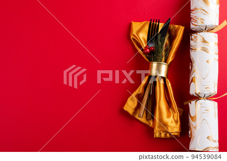 Image of place setting with cutlery, christmas cracker and copy space on red background Image of place setting with cutlery, christmas cracker and copy space on red background 94539084