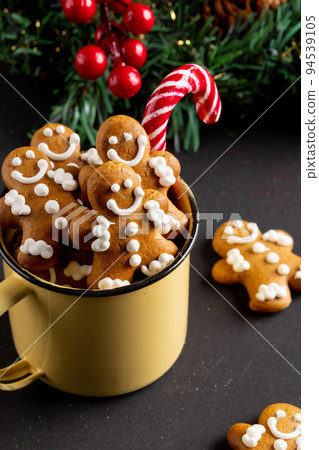 Image of yellow mug with christmas gingerbread men and candy cane on black background 94539105