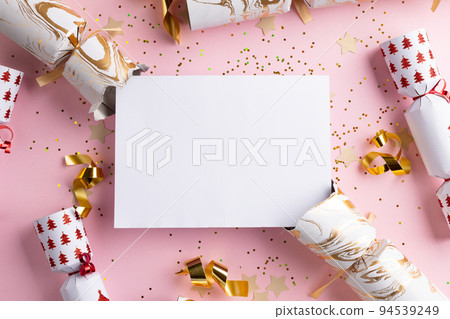 Image of christmas crackers with christmas decoration and white card with copy space on pink Image of christmas crackers with christmas decoration and white card with copy space on pink 94539249