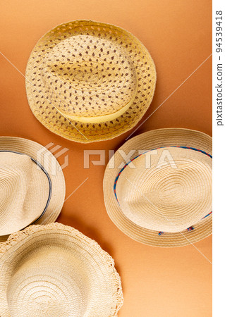 Vertical image of straw hats on yellow surface Vertical image of straw hats on yellow surface 94539418