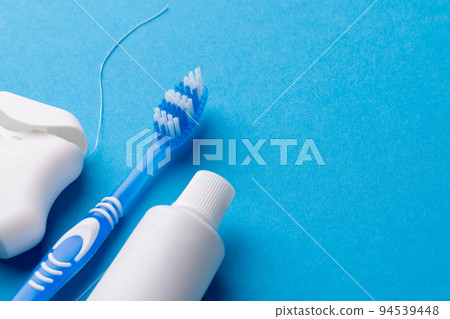 Image of toothbrush, toothpaste and dental string on blue surface 94539448