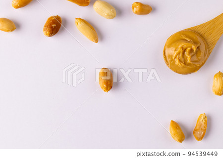 Image of spoon with peanut butter and nuts on white surface 94539449