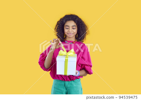 Happy little child receives a birthday present and unties the bow on the gift box 94539475