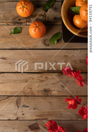 Composition of red flowers and oranges on wooden background 94539791