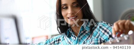 Young woman tunes guitar for music practice Young woman tunes guitar for music practice 94540139