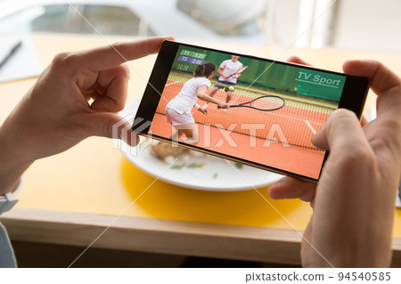 Hands of caucasian man at restaurant tennis match on smartphone 94540585