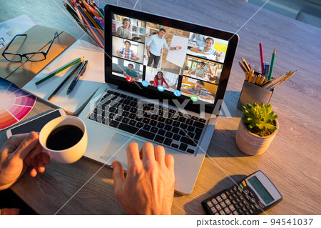 Hands of man using laptop for video call, with smiling diverse elementary school pupils on screen Hands of man using laptop for video call, with smiling diverse elementary school pupils on screen 94541037