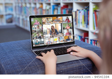 Caucasian girl using laptop for video call, with diverse elementary school pupils on screen Caucasian girl using laptop for video call, with diverse elementary school pupils on screen 94541104