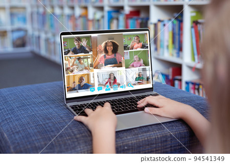 Caucasian girl using laptop for video call, with smiling diverse elementary school pupils on screen Caucasian girl using laptop for video call, with smiling diverse elementary school pupils on screen 94541349