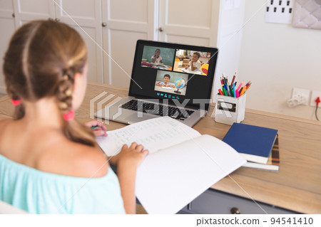 Caucasian girl using laptop for video call, with diverse elementary school pupils on screen Caucasian girl using laptop for video call, with diverse elementary school pupils on screen 94541410