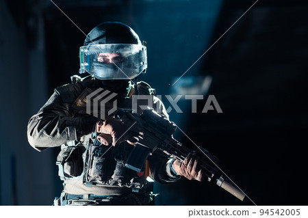Army soldier in Combat Uniforms with an assault rifle and combat helmet night mission dark background. Blue and purple gel light effect. Army soldier in Combat Uniforms with an assault rifle and combat helmet night mission dark background. Blue and purple gel light effect. 94542005