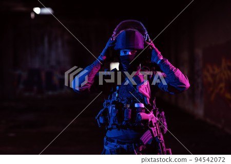 Army soldier in Combat Uniforms with an assault rifle and combat helmet night mission dark background. Blue and purple gel light effect.  94542072