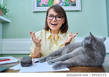 Positive woman looking at webcam, home workplace with pet sleeping cat 94542173