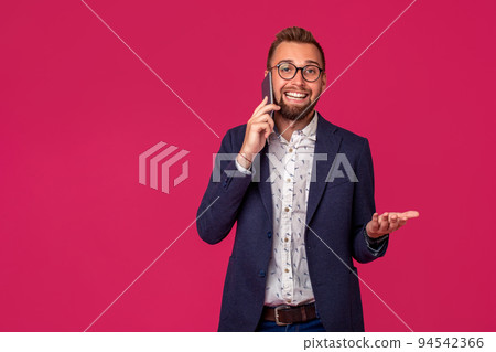 Young cheerful lawyer or businessman is standing on the pink background and smiling, talking on the phone 94542366