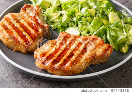 Healthy food grilled pork chop with fresh salad of avocado, brussels sprouts, lettuce close-up in a plate. horizontal 94543368