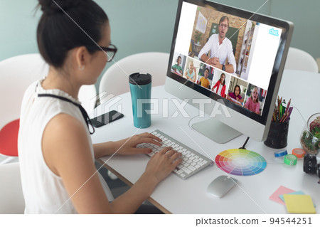 Asian girl using computer for video call, with smiling diverse elementary school pupils on screen Asian girl using computer for video call, with smiling diverse elementary school pupils on screen 94544251