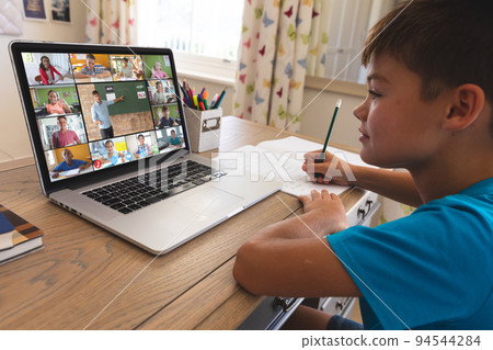 Caucasian boy using laptop for video call, with smiling diverse elementary school pupils on screen Caucasian boy using laptop for video call, with smiling diverse elementary school pupils on screen 94544284