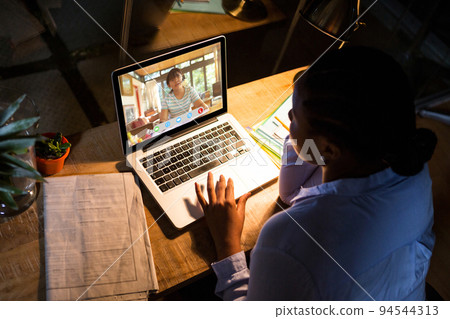African american woman using laptop for video call, with high school pupil on screen 94544313