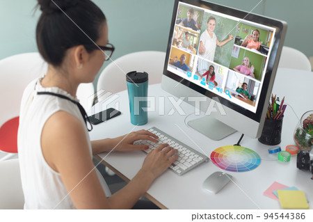 Asian girl holding computer for video call, with smiling diverse elementary school pupils on screen Asian girl holding computer for video call, with smiling diverse elementary school pupils on screen 94544386