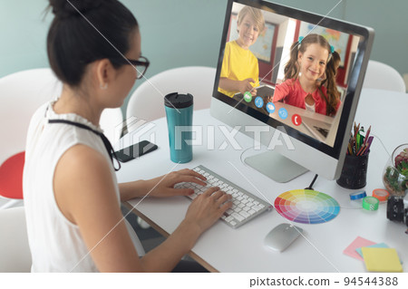 Asian girl holding computer for video call, with smiling elementary school pupils on screen Asian girl holding computer for video call, with smiling elementary school pupils on screen 94544388