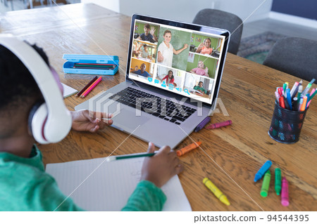 African american boy using laptop for video call, with diverse elementary school pupils on screen 94544395