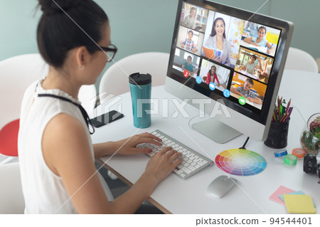 Asian girl holding computer for video call, with smiling diverse elementary school pupils on screen Asian girl holding computer for video call, with smiling diverse elementary school pupils on screen 94544401