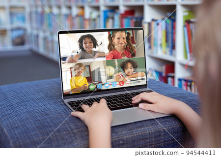 Caucasian girl using laptop for video call, with smiling diverse elementary school pupils on screen Caucasian girl using laptop for video call, with smiling diverse elementary school pupils on screen 94544411