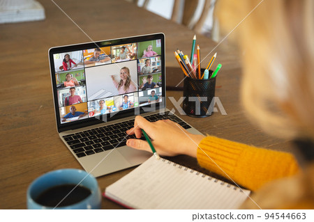 Caucasian woman using laptop for video call, with smiling diverse elementary school pupils on screen Caucasian woman using laptop for video call, with smiling diverse elementary school pupils on screen 94544663