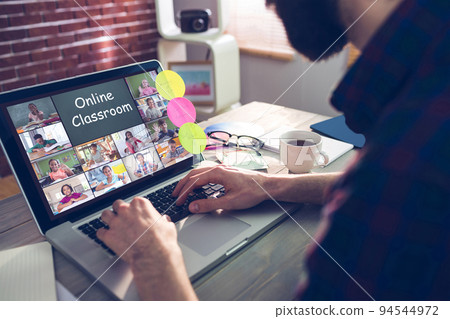 Caucasian man using laptop for video call, with smiling diverse elementary school pupils on screen 94544972