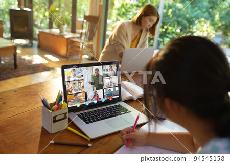 Asian girl using laptop for video call, with smiling diverse elementary school pupils on screen Asian girl using laptop for video call, with smiling diverse elementary school pupils on screen 94545158