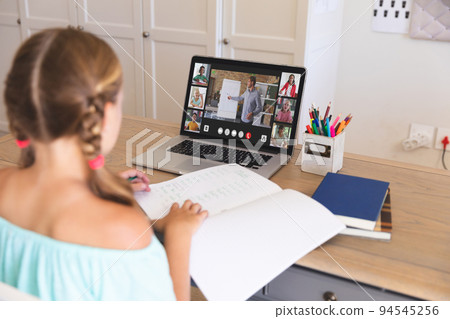 Caucasian girl using laptop for video call, with smiling diverse elementary school pupils on screen Caucasian girl using laptop for video call, with smiling diverse elementary school pupils on screen 94545256