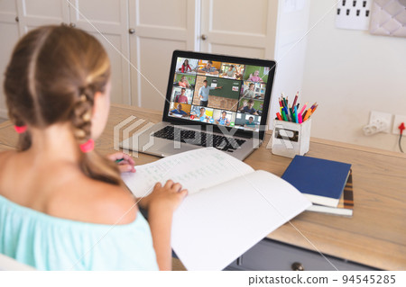 Caucasian girl using laptop for video call, with smiling diverse elementary school pupils on screen Caucasian girl using laptop for video call, with smiling diverse elementary school pupils on screen 94545285