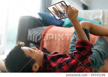 Asian boy using tablet for video call, with smiling diverse high school pupils on screen Asian boy using tablet for video call, with smiling diverse high school pupils on screen 94545286