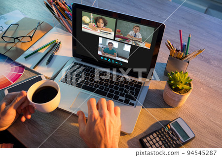 Hands of man using laptop for video call, with smiling diverse elementary school pupils on screen Hands of man using laptop for video call, with smiling diverse elementary school pupils on screen 94545287