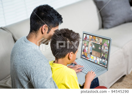 Biracial boy with father using laptop for video call, with elementary school pupils on screen Biracial boy with father using laptop for video call, with elementary school pupils on screen 94545290