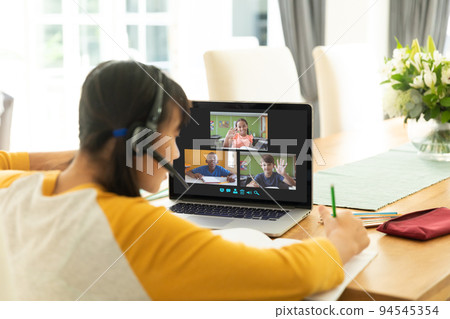 Asian girl using laptop for video call, with waving diverse elementary school pupils on screen Asian girl using laptop for video call, with waving diverse elementary school pupils on screen 94545354