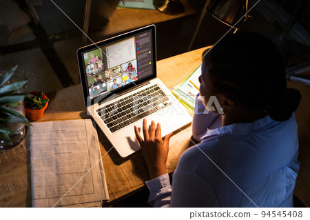 African american woman using laptop for video call, with diverse elementary school pupils on screen African american woman using laptop for video call, with diverse elementary school pupils on screen 94545408