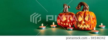 Halloween composition with diy ceramic pumpkins jack lantern and candles on pine green background 94546342