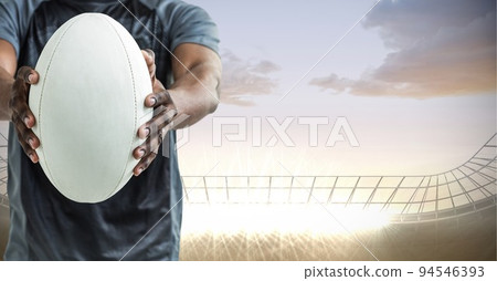 Composition of male rugby player holding rugby ball over sports stadium 94546393