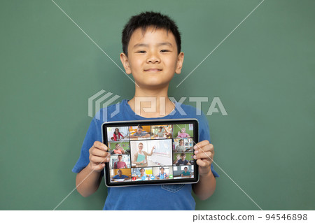 Smiling asian boy holding tablet for video call, with diverse smiling high school pupils on screen Smiling asian boy holding tablet for video call, with diverse smiling high school pupils on screen 94546898