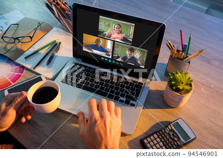 Hands of man using laptop for video call, with waving diverse elementary school pupils on screen Hands of man using laptop for video call, with waving diverse elementary school pupils on screen 94546901