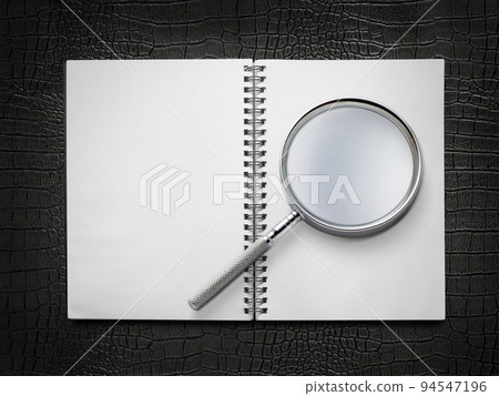 Open book closeup with turning pages and magnifying loupe. book in hard cover. Studying and research concept 94547196