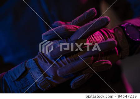 Photo of a fully equipped soldier in black armor tactical vest and gloves standing on black background closeup front view. Photo of a fully equipped soldier in black armor tactical vest and gloves standing on black background closeup front view. 94547219