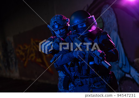 Modern warfare soldiers in dark with combat ammunition and weapons in the hands of equipped laser sights are in battle order. Mixed media.  94547231